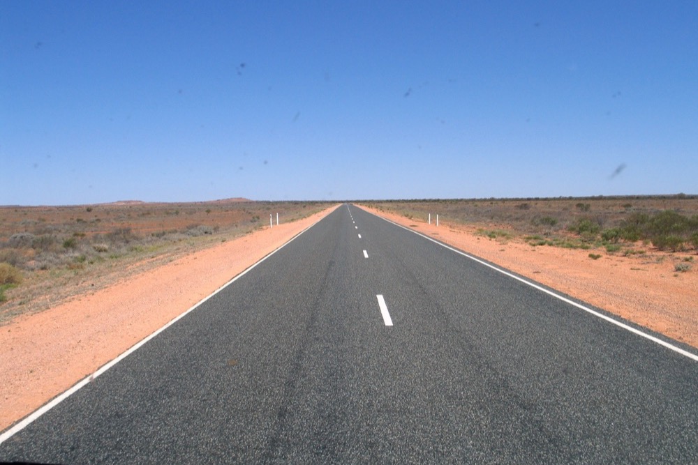 A long, straight outback highway stretching to the horizon